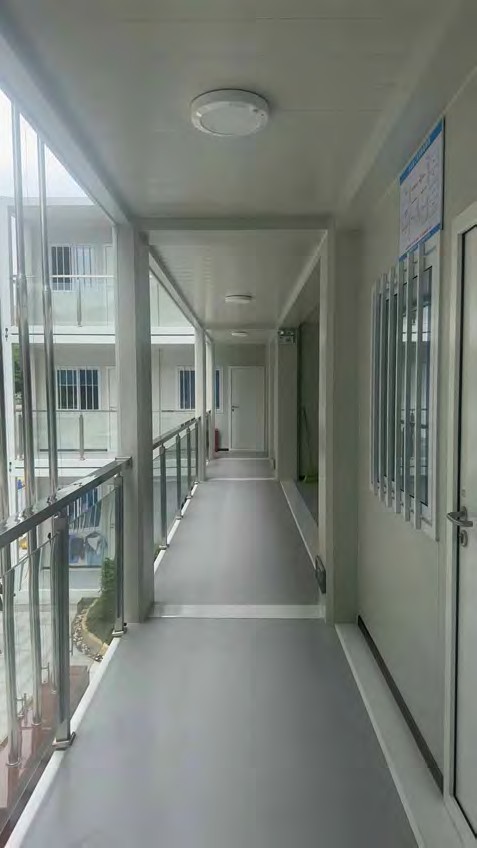 Enclosed external walkway on the upper floor of a modular building, glazed on one side with doors to offices on the other